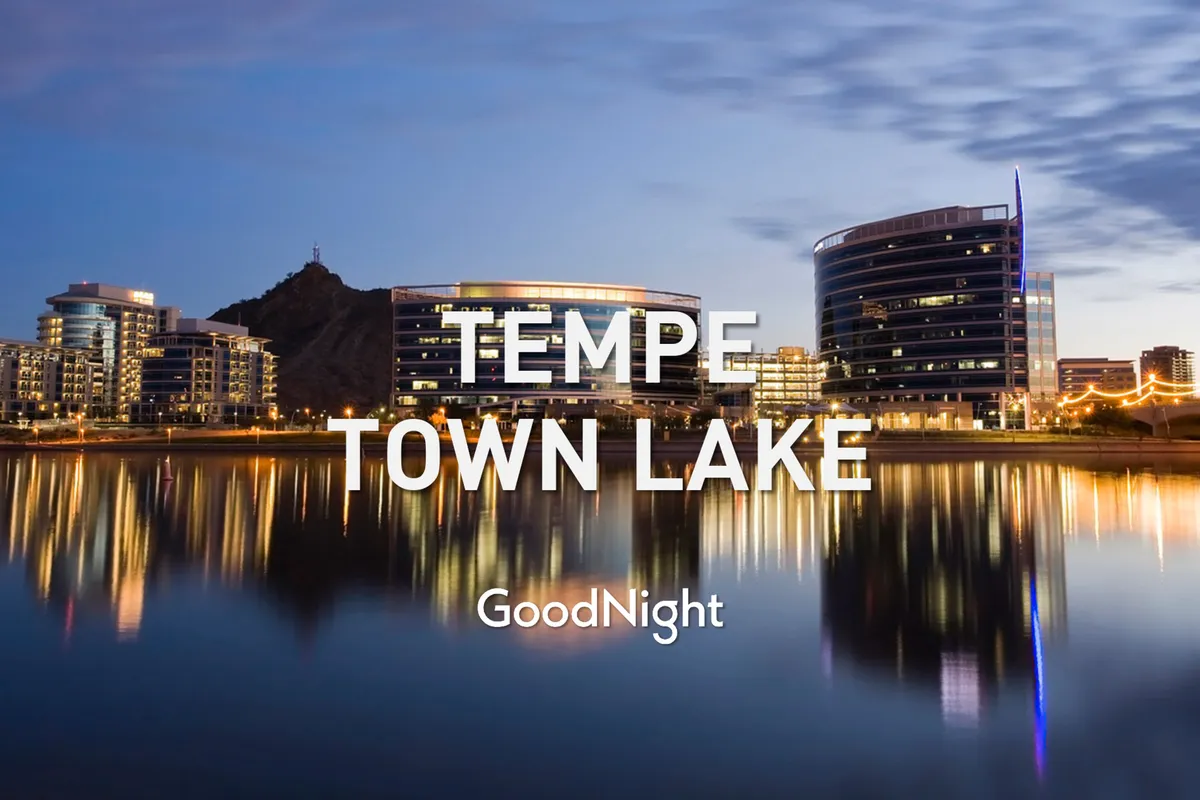 A sweeping view of Tempe Town Lake with modern buildings lining the shore and mountains as a backdrop. The scene is tranquil yet lively, suggesting opportunities for lakeside dining, evening strolls, and participation in community events—activities that support a work-life balance and easy connectivity to city attractions.