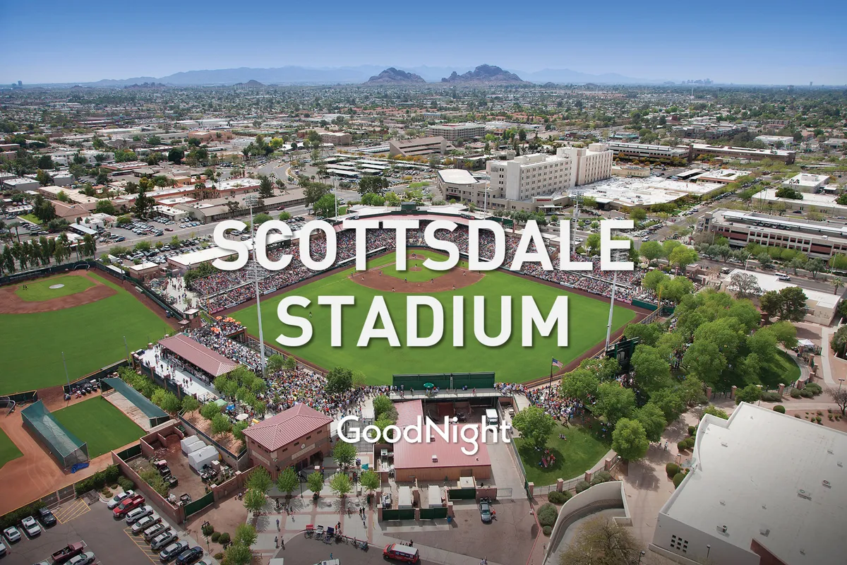 Scottsdale Stadium comes alive in this image, with a packed crowd, players on the baseball field, and scenic mountain views behind. Fans are seen celebrating and enjoying the festive atmosphere, highlighting one of Old Town's most iconic attractions.