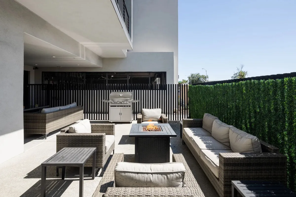 A cozy exterior scene highlighting a fire pit encircled by comfortable outdoor seating and a grill nearby. The area invites guests to socialize, enjoy barbecues, or gather for evening conversations under the stars.