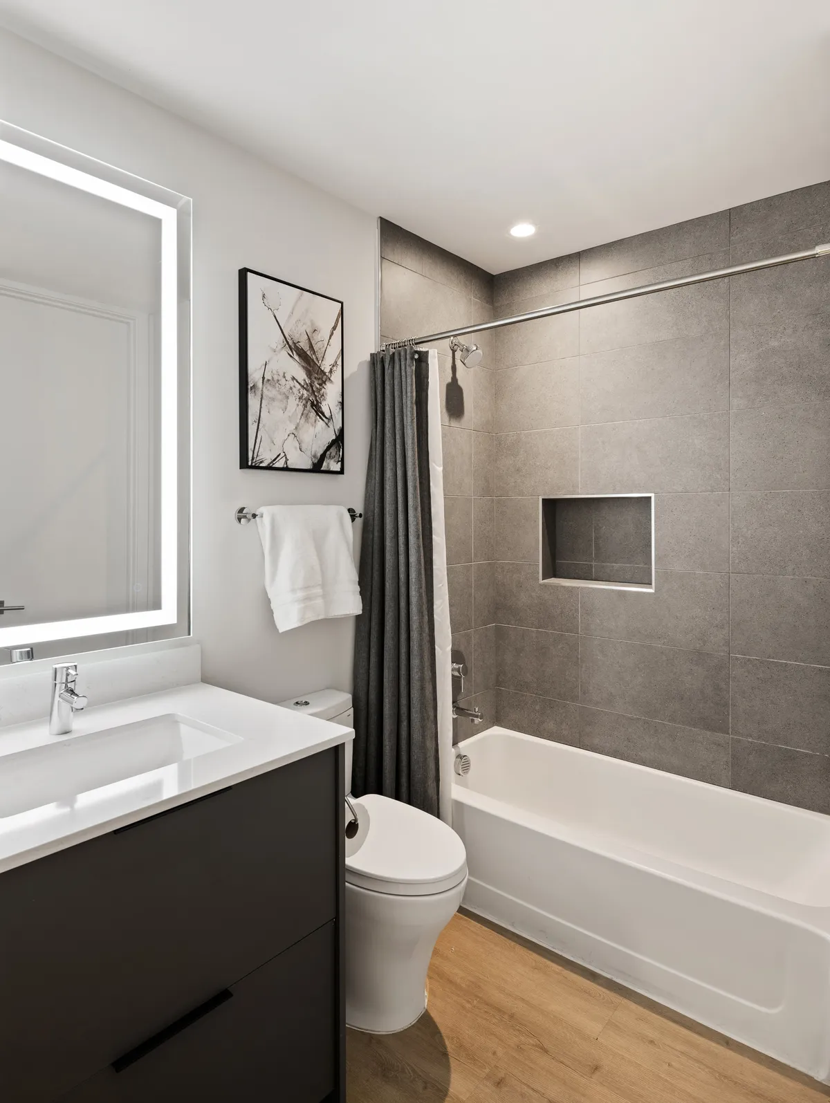 An elegant bathroom featuring a deep soaking bathtub, spacious vanity, and stylish wall art. The serene, well-lit space promises relaxation and a luxurious bathing experience.